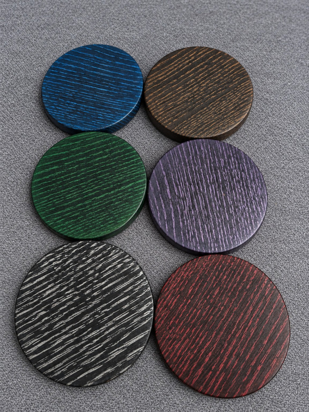 Overhead view of six ebonised oak coasters showing the available grain highlight colours