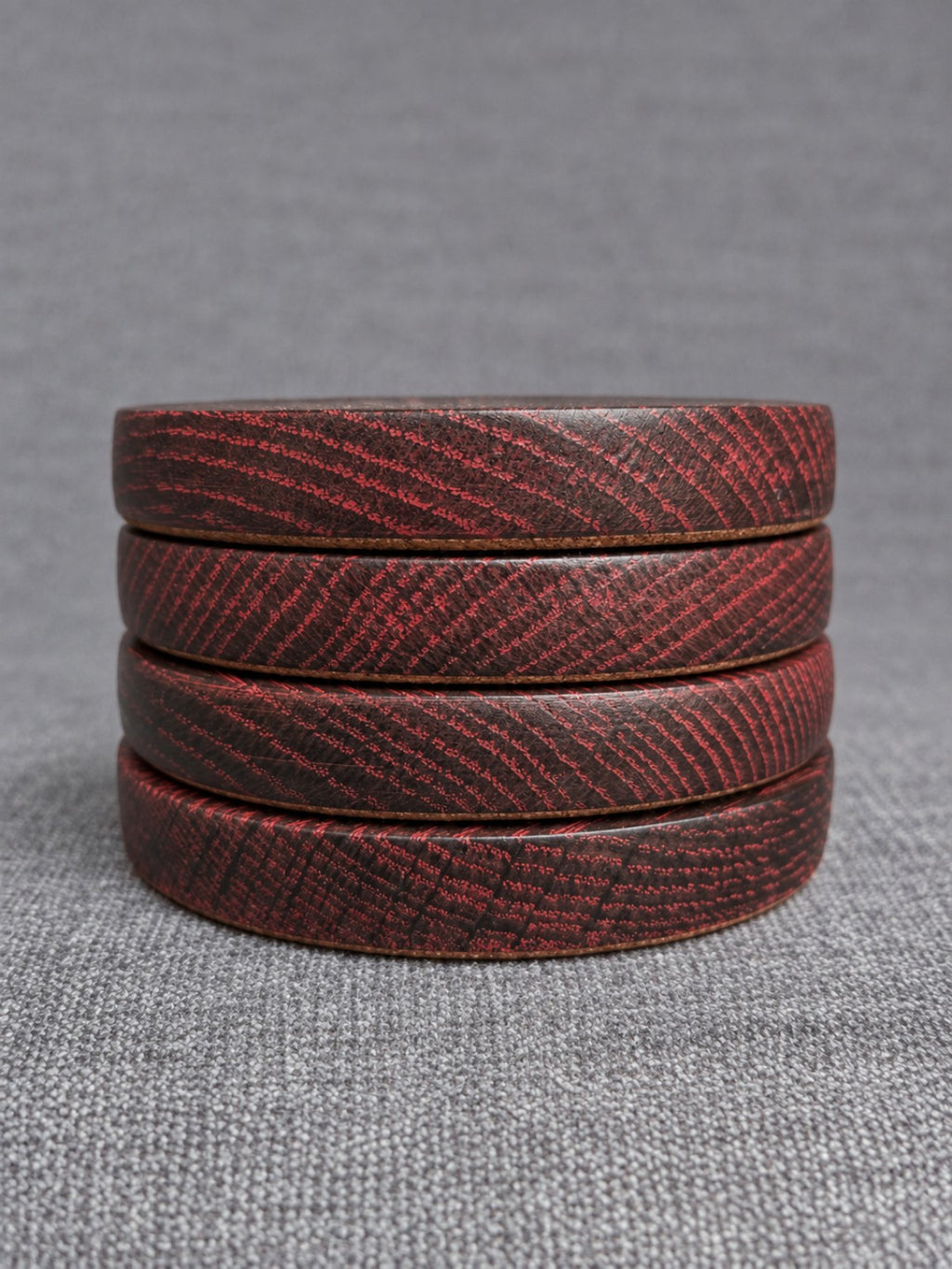 Four red grain ebonised oak coasters stacked to show their finished edges