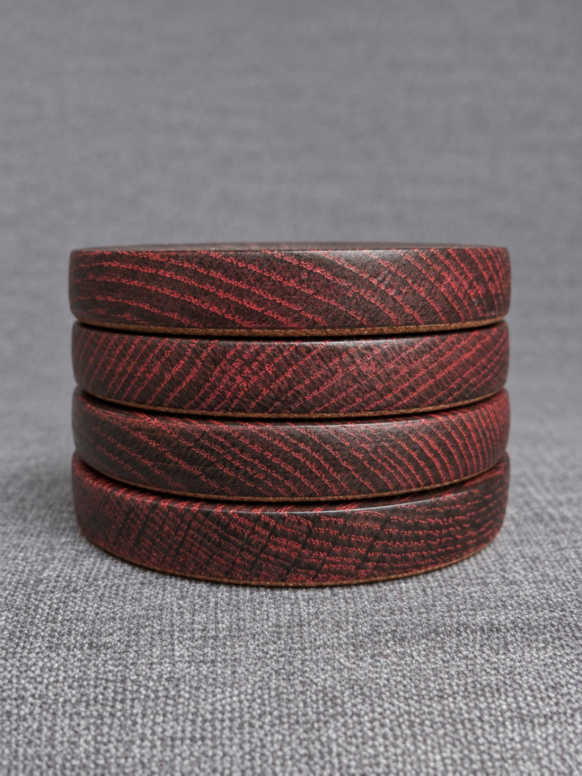 Four red grain ebonised oak coasters stacked to show their finished edges