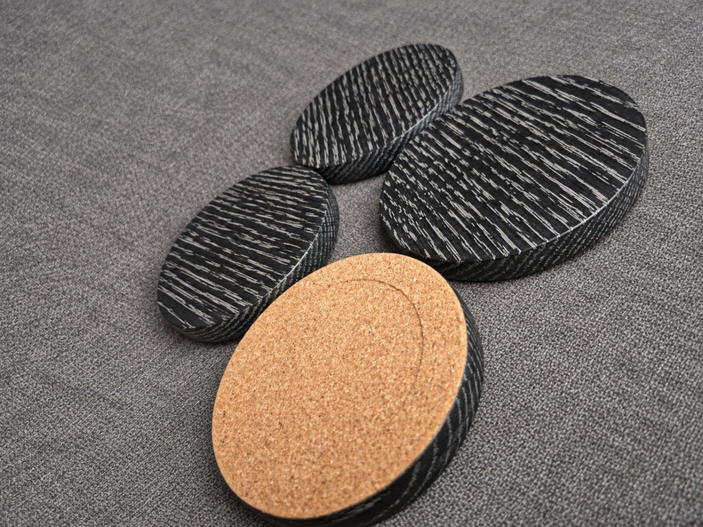 White grain ebonised oak coasters with one turned over to show the fitted cork backing