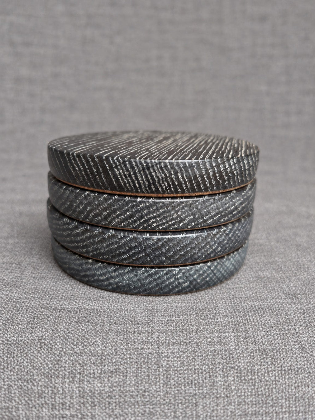 Stacked ebonised oak coasters with white highlighted grain