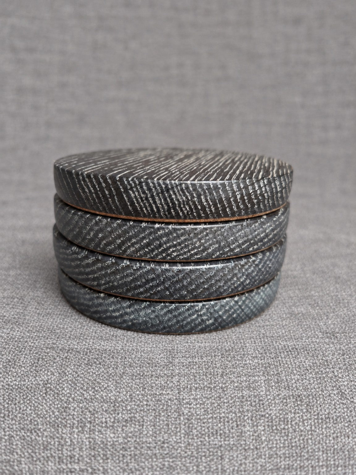 Stacked ebonised oak coasters with white highlighted grain