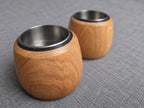 Two handmade oak tealight holders showing their stainless steel inserts and rounded wood grain