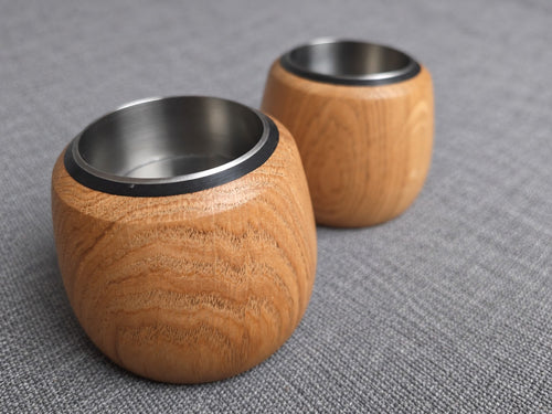 Two handmade oak tealight holders showing their stainless steel inserts and rounded wood grain