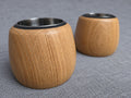 Two unlit oak tealight holders with softly rounded sides and fitted stainless steel inserts