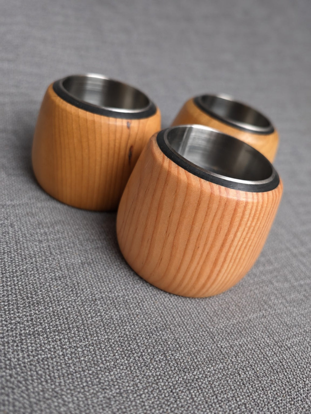 Angled view of the three wooden tealight holders showing their stainless steel inserts