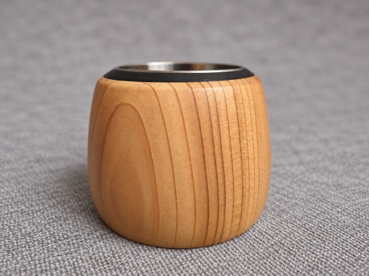 Close view of a rounded wooden holder from the trio, showing curved grain and the dark rim around its insert
